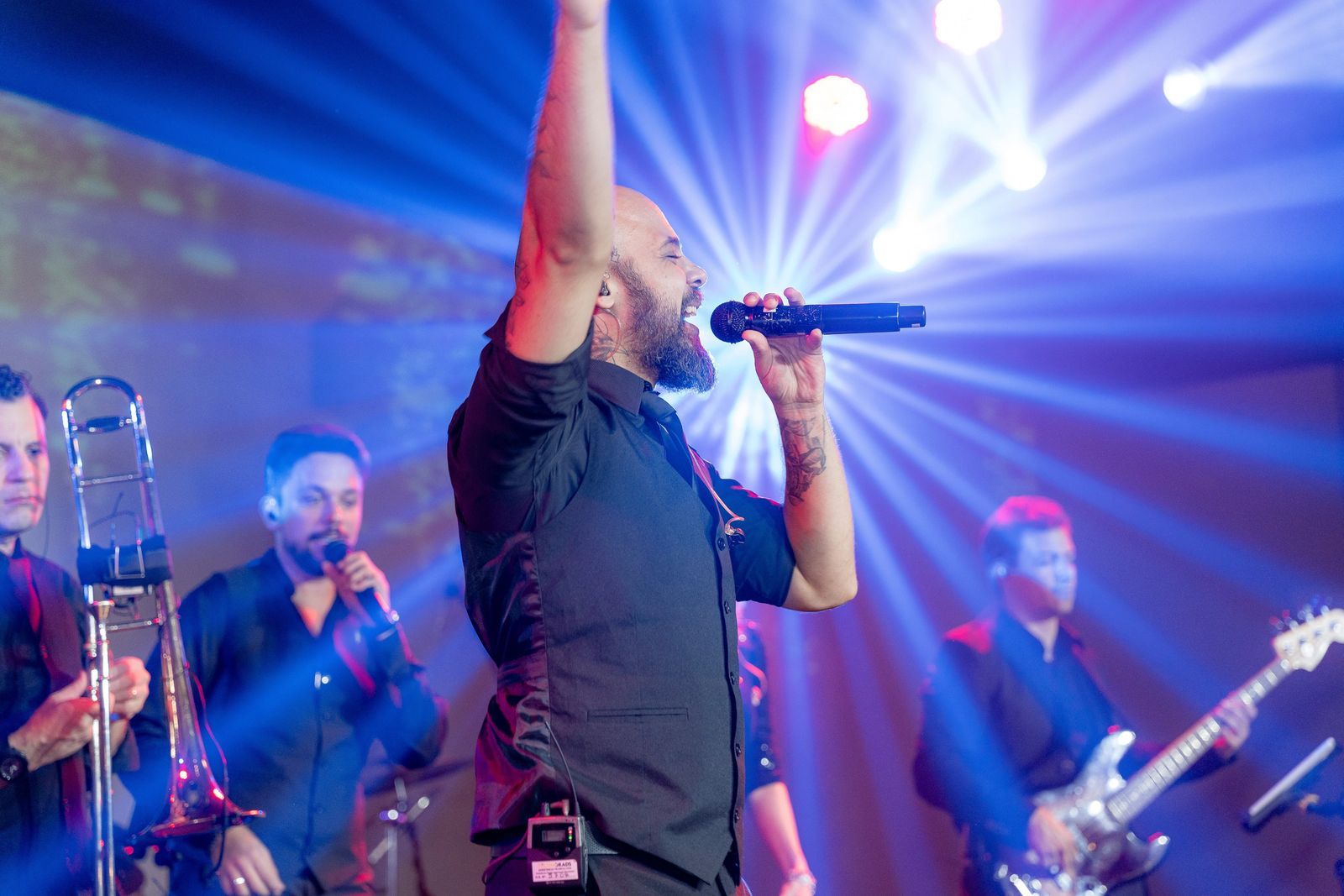 Cantores da Banda The Flavours no palco com o público sob feixes de luz azul