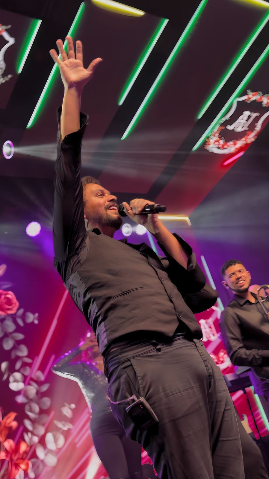 Cantor da The Flavours com o braço erguido animando a festa